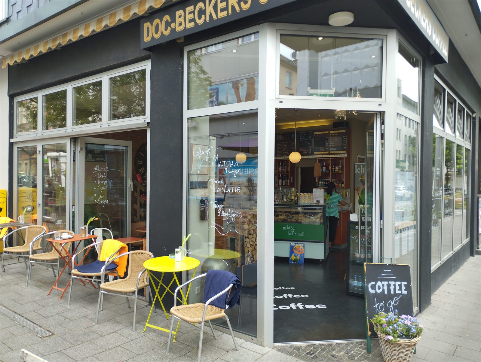 Sonniger Außenbereich von Doc-Beckers Coffee mit Tischen an der Fußgängerzone Kortumstraße